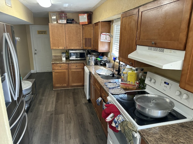 kitchen featuring under cabinet range hood, brown cabinets, appliances with stainless steel finishes, and a sink