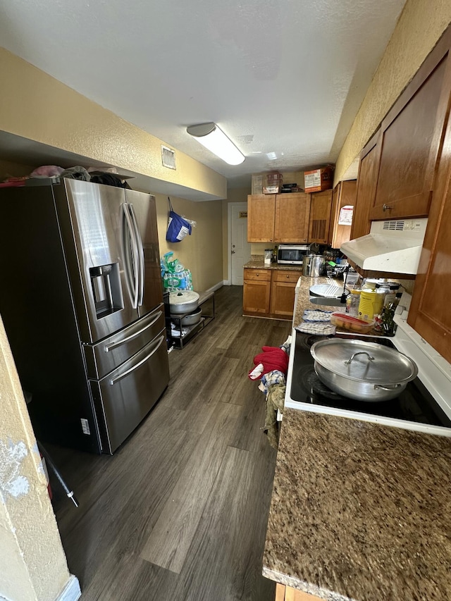 kitchen featuring visible vents, dark wood-style flooring, stainless steel refrigerator with ice dispenser, exhaust hood, and brown cabinets