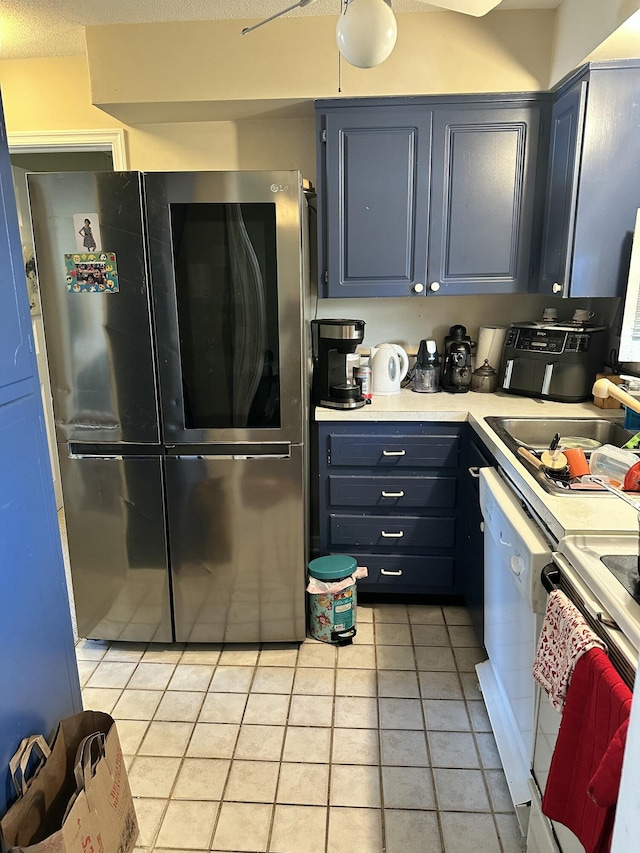 148 Yacht Club Dr Unit 13, North Palm Beach, FL 33408 - kitchen featuring a sink, blue cabinets, white appliances, light tile patterned floors, and light countertops