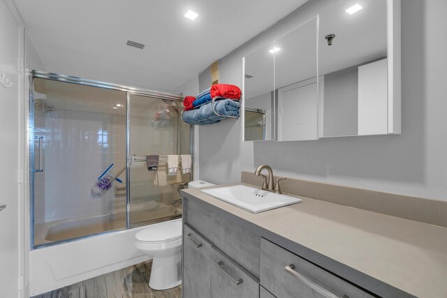 7240 Huntington Ln Unit 802, Delray Beach, FL 33446 - bathroom with toilet, vanity, wood finished floors, visible vents, and shower / bath combination with glass door