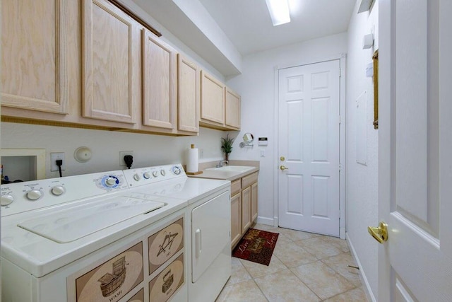 clothes washing area featuring baseboards, light tile patterned flooring, cabinet space, a sink, and washer and clothes dryer