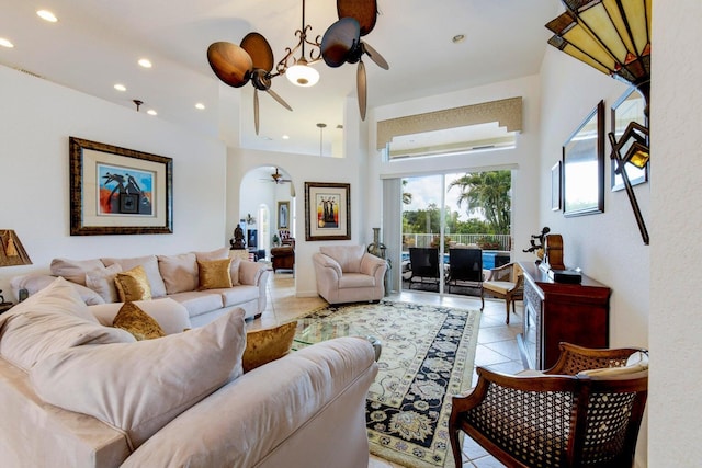 living room with light tile patterned floors, recessed lighting, arched walkways, ceiling fan, and a towering ceiling