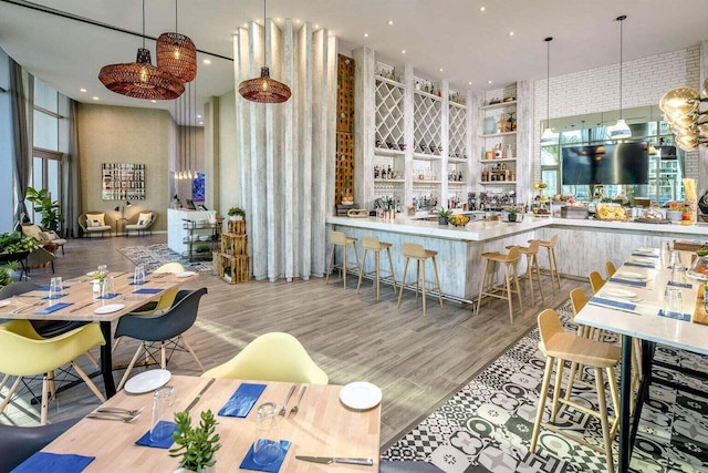 dining room with indoor wet bar, wood finished floors, and a towering ceiling