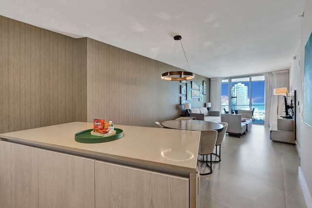 kitchen with a wall of windows, light countertops, modern cabinets, open floor plan, and a center island