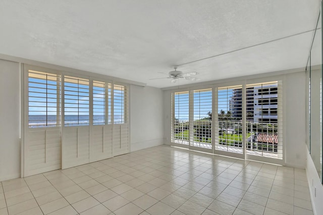 tiled empty room featuring a ceiling fan