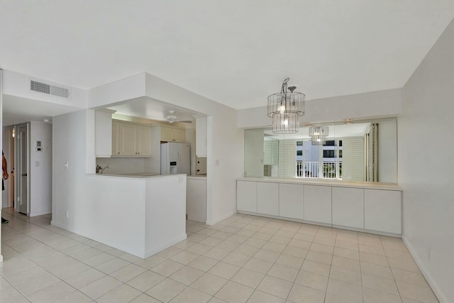 kitchen featuring visible vents, white refrigerator with ice dispenser, a peninsula, light countertops, and light tile patterned floors