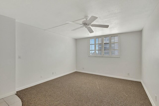 carpeted empty room featuring a ceiling fan and baseboards