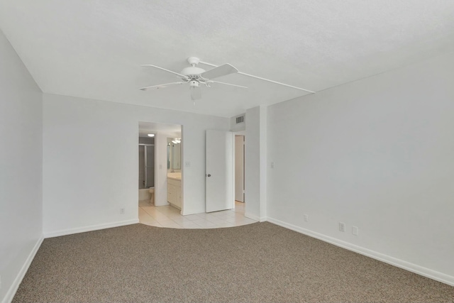 empty room featuring light tile patterned floors, light colored carpet, baseboards, and ceiling fan