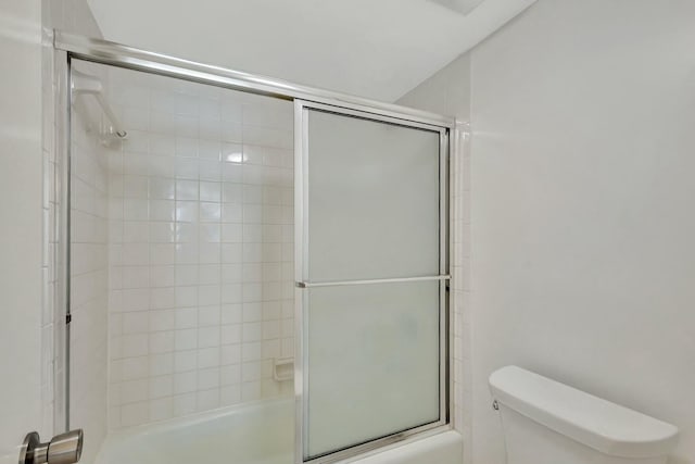 bathroom featuring toilet and bath / shower combo with glass door