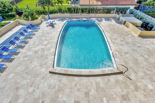 community pool with a patio and fence