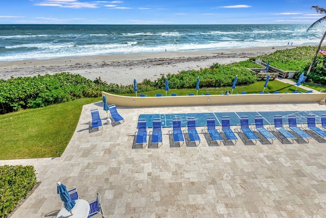 view of swimming pool with a yard, a view of the beach, and a water view