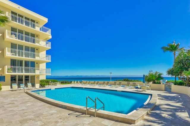 pool featuring a patio and a water view