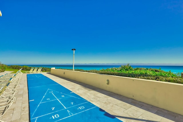 surrounding community with a water view and shuffleboard