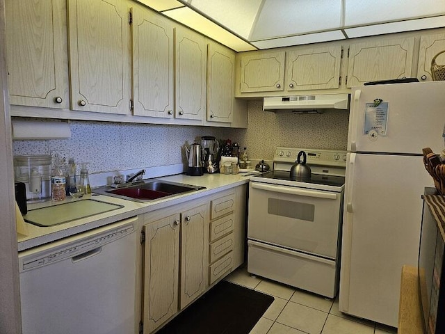 kitchen featuring under cabinet range hood, light countertops, light tile patterned floors, white appliances, and a sink