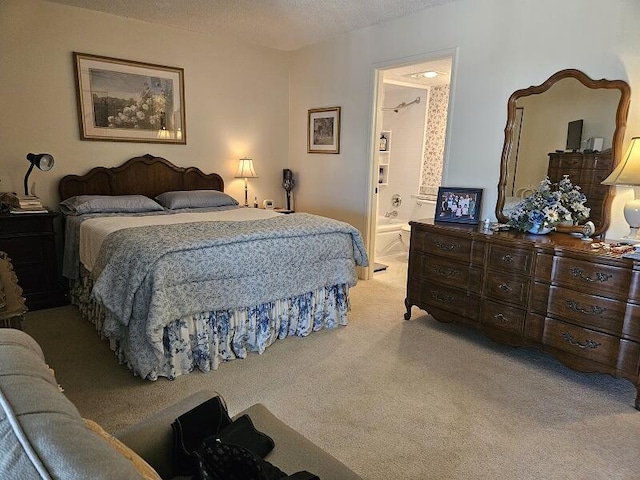 bedroom with light carpet, a textured ceiling, and ensuite bath