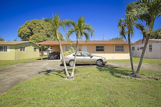 manufactured / mobile home featuring stucco siding, driveway, fence, a front yard, and an attached carport