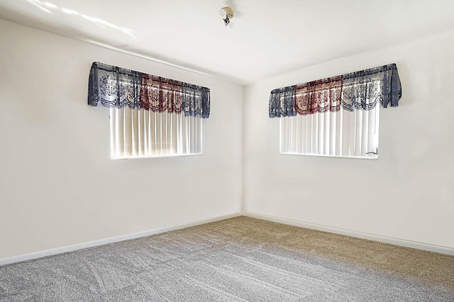 carpeted empty room featuring a healthy amount of sunlight and baseboards