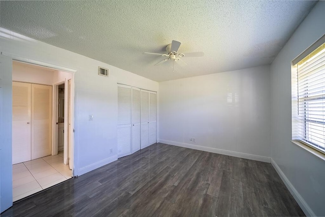 unfurnished bedroom with visible vents, baseboards, a textured ceiling, and wood finished floors