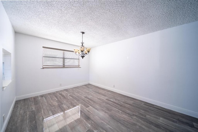 unfurnished room with a notable chandelier, baseboards, dark wood-style flooring, and a textured ceiling