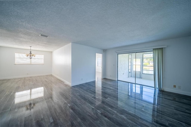 unfurnished room with baseboards, visible vents, dark wood-style flooring, and a chandelier