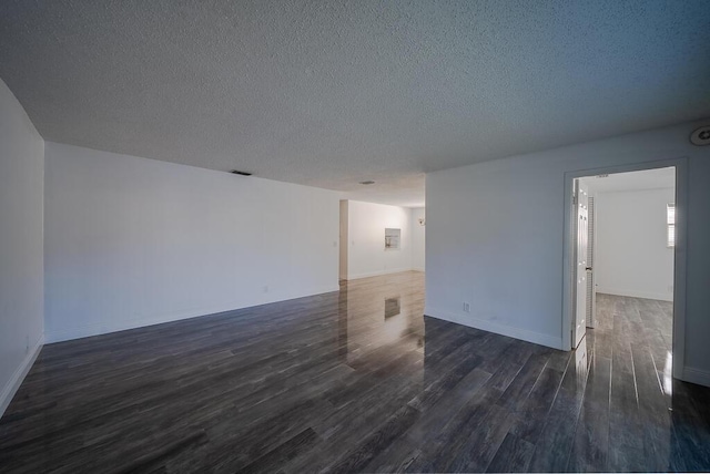 unfurnished room featuring visible vents, a textured ceiling, dark wood-type flooring, and baseboards