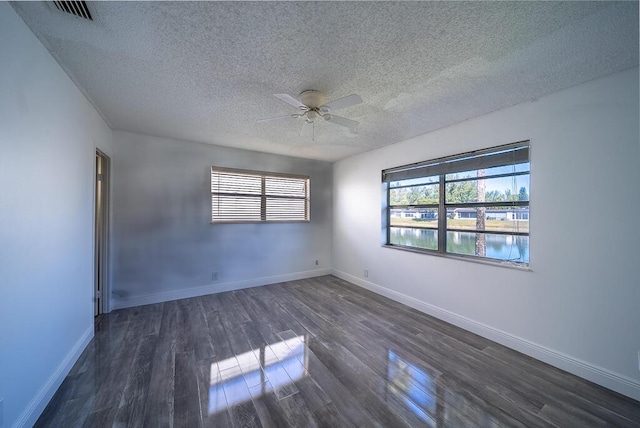 spare room featuring visible vents, baseboards, dark wood-type flooring, and ceiling fan