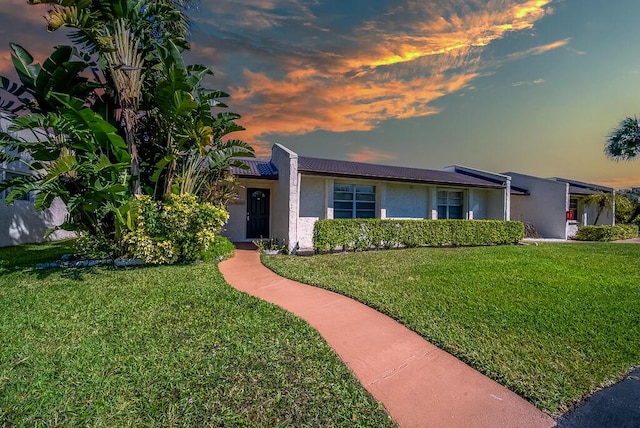 ranch-style home with a tile roof, a lawn, and stucco siding