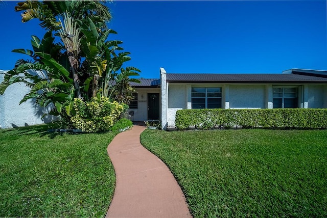 view of front of house featuring a front lawn, a tile roof, and stucco siding