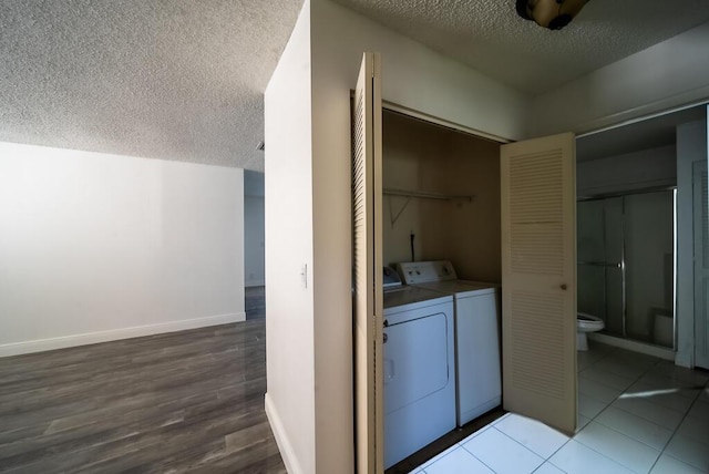 washroom featuring washing machine and clothes dryer, tile patterned flooring, baseboards, laundry area, and a textured ceiling