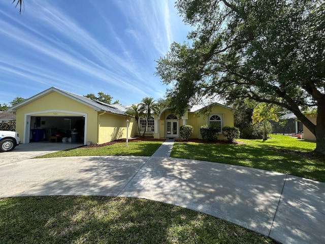 view of front of property with a front yard, driveway, an attached garage, stucco siding, and french doors