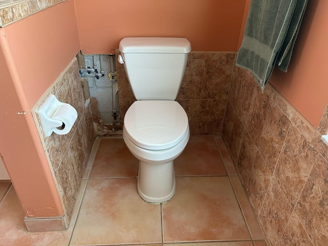 bathroom featuring a wainscoted wall, toilet, tile walls, and tile patterned flooring