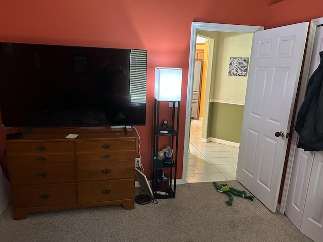 bedroom with light tile patterned floors, light carpet, and freestanding refrigerator