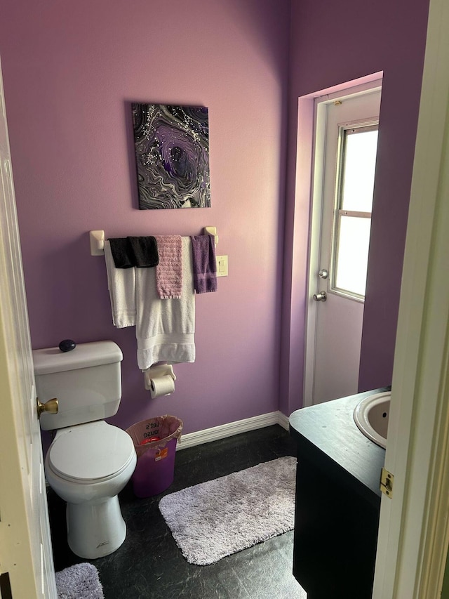 half bath featuring toilet, vanity, and baseboards