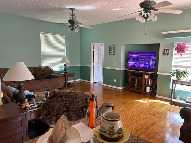 living area featuring a wealth of natural light, wood finished floors, a textured ceiling, and ceiling fan