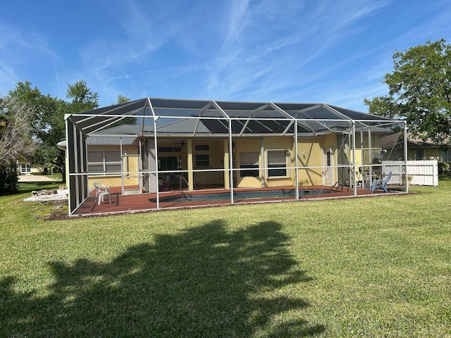 back of house with glass enclosure, a yard, a patio area, and an outdoor pool