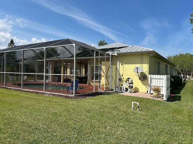 rear view of house featuring glass enclosure, a yard, an outdoor pool, stucco siding, and metal roof