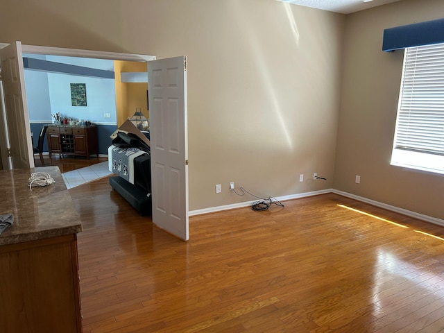 unfurnished room with baseboards and hardwood / wood-style flooring