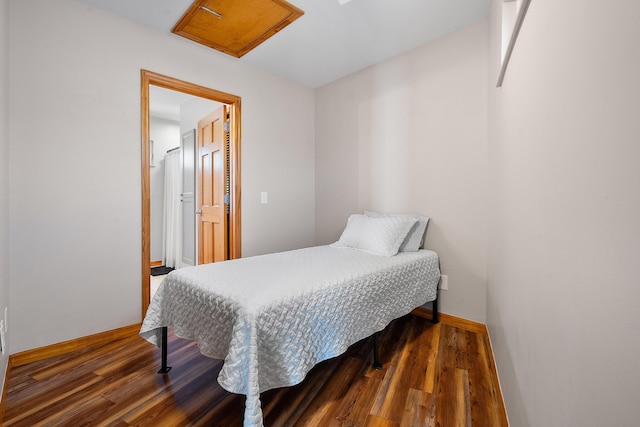 bedroom with baseboards, attic access, and wood finished floors