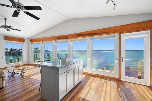 sunroom with visible vents, a water view, track lighting, lofted ceiling, and ceiling fan