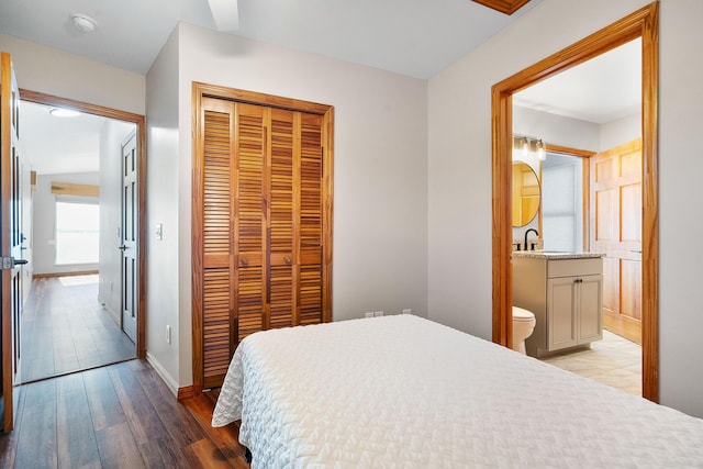 bedroom featuring a sink, a closet, connected bathroom, light wood-style floors, and baseboards