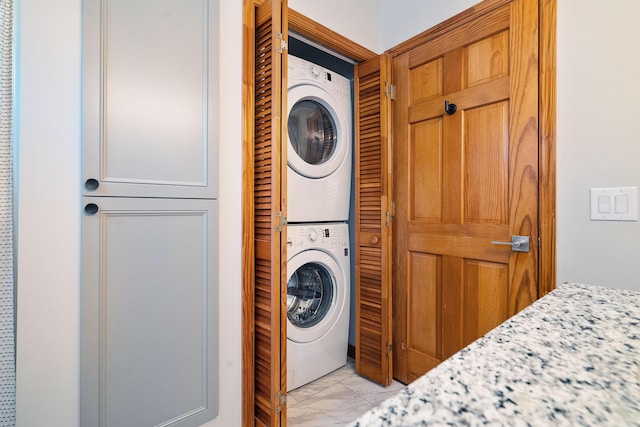 washroom with light tile patterned floors, laundry area, and stacked washer and dryer