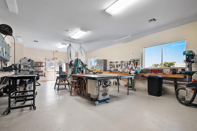 miscellaneous room featuring visible vents, a workshop area, a textured ceiling, and concrete flooring