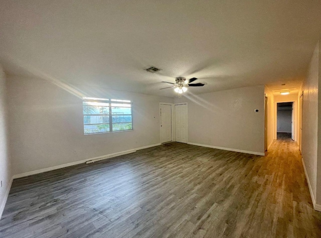 unfurnished room with baseboards, wood finished floors, visible vents, and ceiling fan