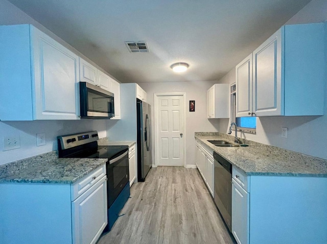 kitchen featuring visible vents, a sink, appliances with stainless steel finishes, white cabinets, and light wood finished floors