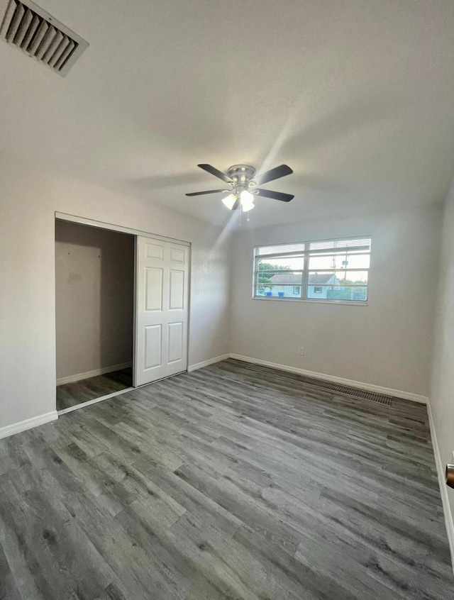 unfurnished bedroom with a closet, visible vents, baseboards, and wood finished floors