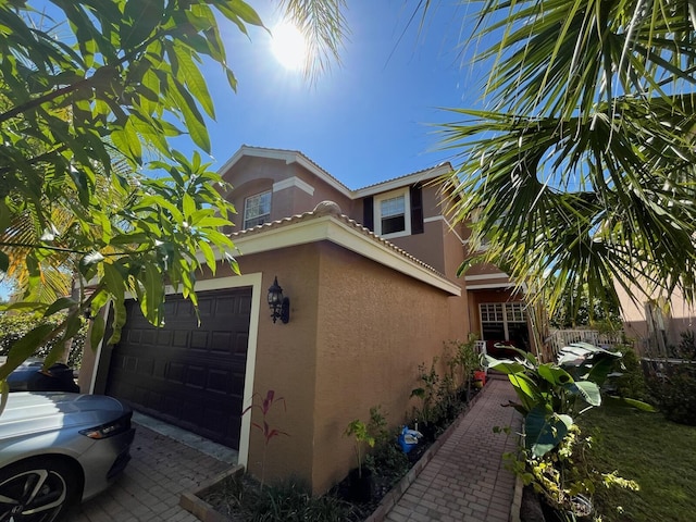 view of property exterior with stucco siding, an attached garage, and a tile roof