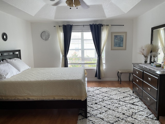 bedroom with baseboards, a textured ceiling, light wood-style floors, and a ceiling fan