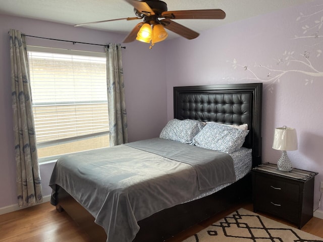 bedroom with wood finished floors, baseboards, and ceiling fan