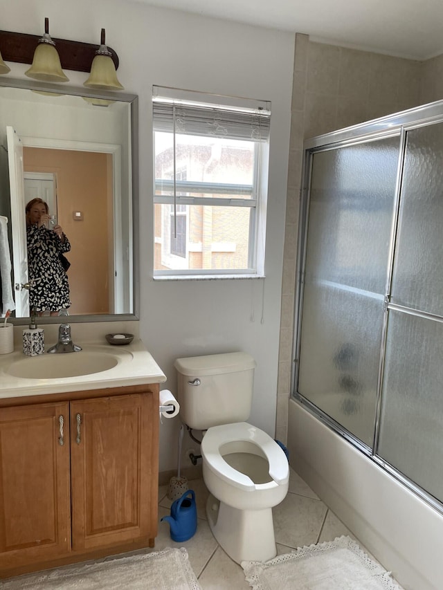 full bath featuring tile patterned flooring, toilet, vanity, and shower / bath combination with glass door