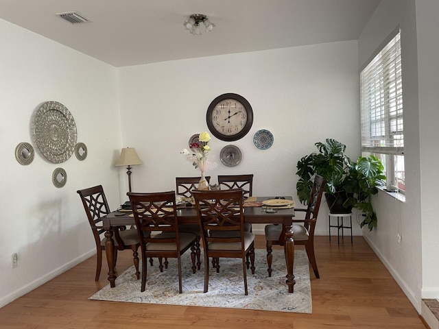 dining space featuring wood finished floors, visible vents, and baseboards